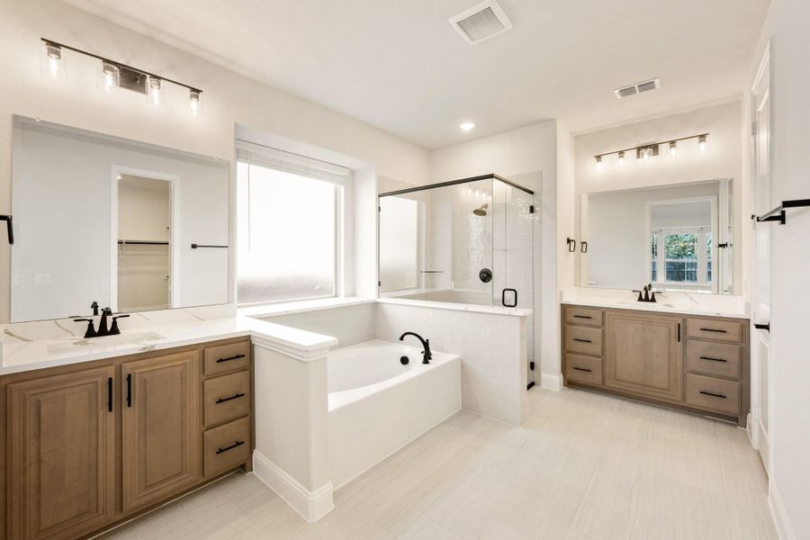 Master bathroom with dual wood vanities, soaking tub, glass shower, and white tile floors Master bathroom with dual wood vanities, soaking tub, glass shower, and white tile floors