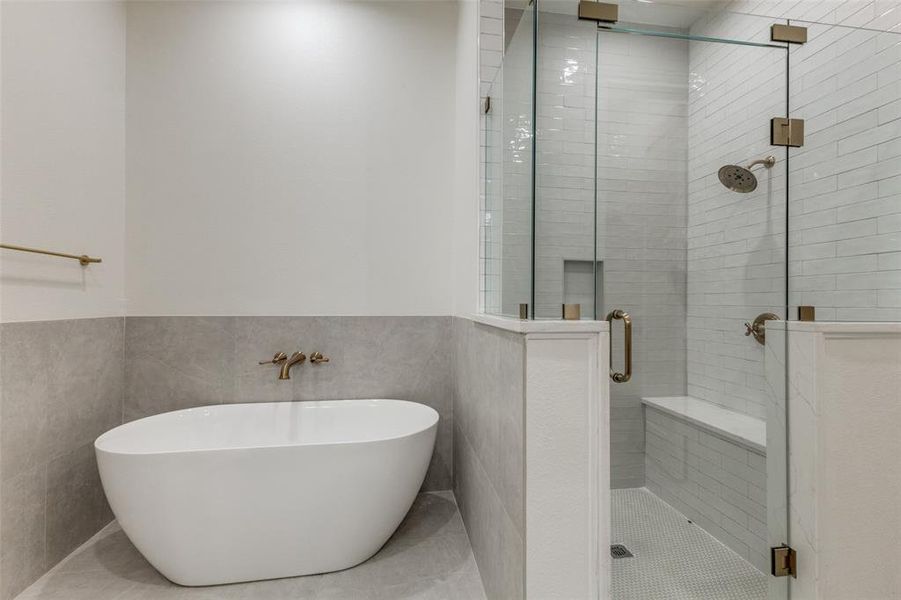 Full bathroom with a shower stall, a soaking tub, tile walls, and wainscoting