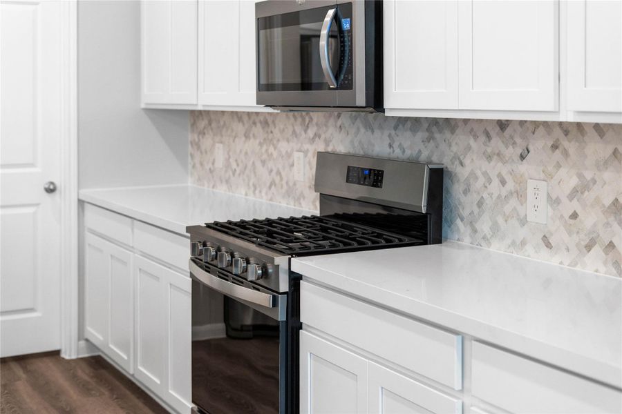 Showcased here is a Whirlpool gas range with center oval burner, paired with a steam microwave equipped with sensor cooking—all framed by an elegant tile backsplash.