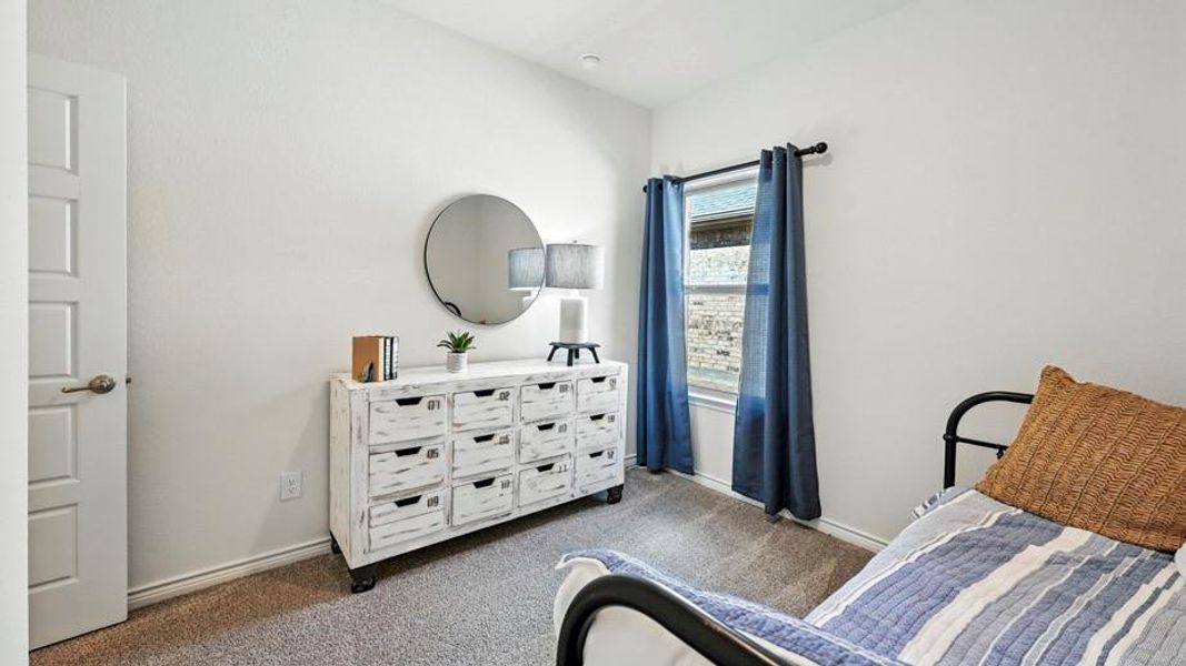 Carpeted room featuring a window with dark blue curtains, white walls, and a five-panel interior door with a brushed nickel handle