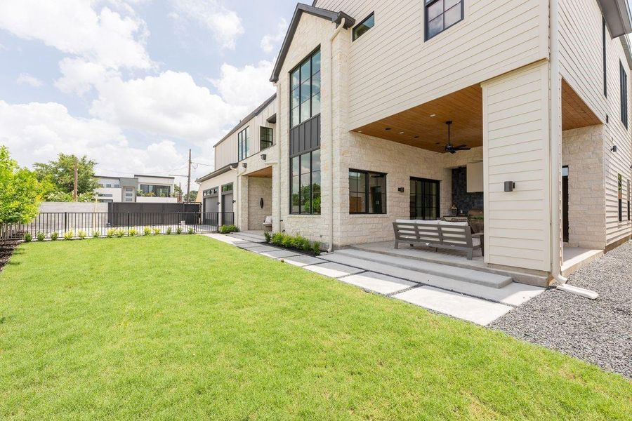 A striking composition of stone, siding, and steel-framed glass, this backyard façade captures modern craftsmanship at its finest. From open-air dining beneath ceiling fans to evenings gathered on the sculpted deck, every detail supports elevated everyday living.