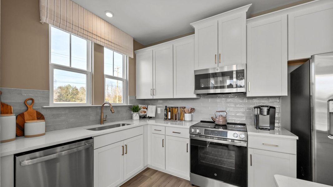The Rochester Plan by DRB homes kitchen with white cabinets and silver appliances in Charlotte, NC.