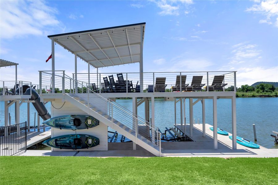 Two-story boat dock structure featuring a covered upper deck, two boat lifts, expanse of green lawn.