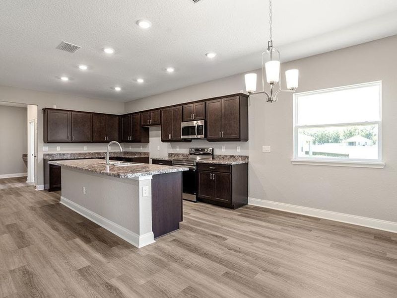 Meals are a delight in your beautiful kitchen with seating at the island and adjacent sunny dining cafe - Monroe 55+ by Highland Homes