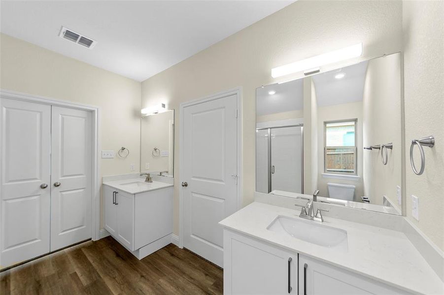 Dual white vanities with integrated sinks, each featuring a polished chrome faucet and quartz-finish countertop