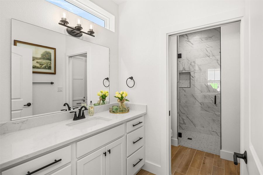 A sleek white vanity with a large mirror and contemporary fixtures defines this naturally illuminated bathroom.
