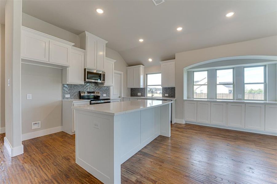 Kitchen featuring white cabinetry, a center island, stainless steel appliances, dark hardwood / wood-style flooring, and lofted ceiling