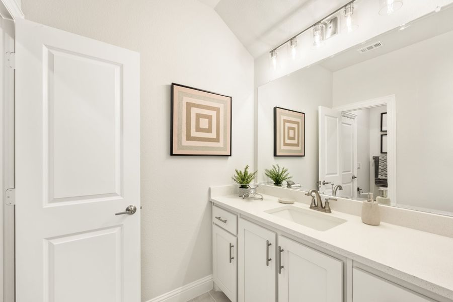 Bathroom with white vanity, single sink, large mirror, and wall art above the cabinet