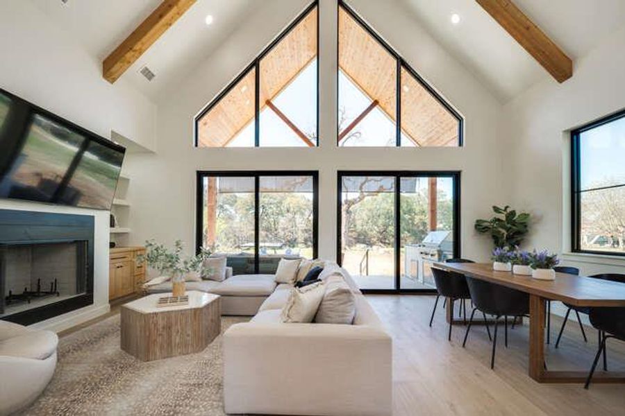 Living room with beam ceiling, high vaulted ceiling, a fireplace, and light wood-style floors