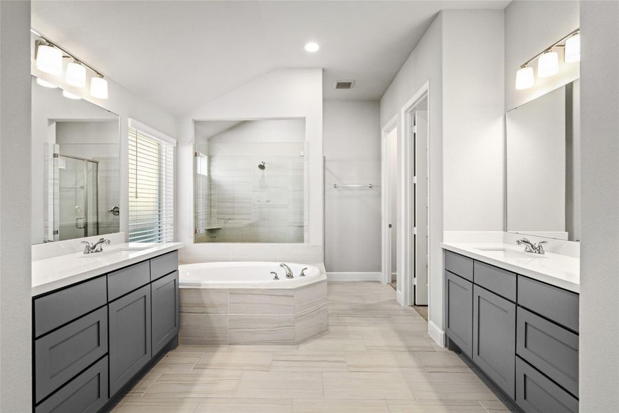 Luxurious Primary Bathroom featuring Dual Vanities, a separate walk-in shower, and a deep soaking tub centerpiece.