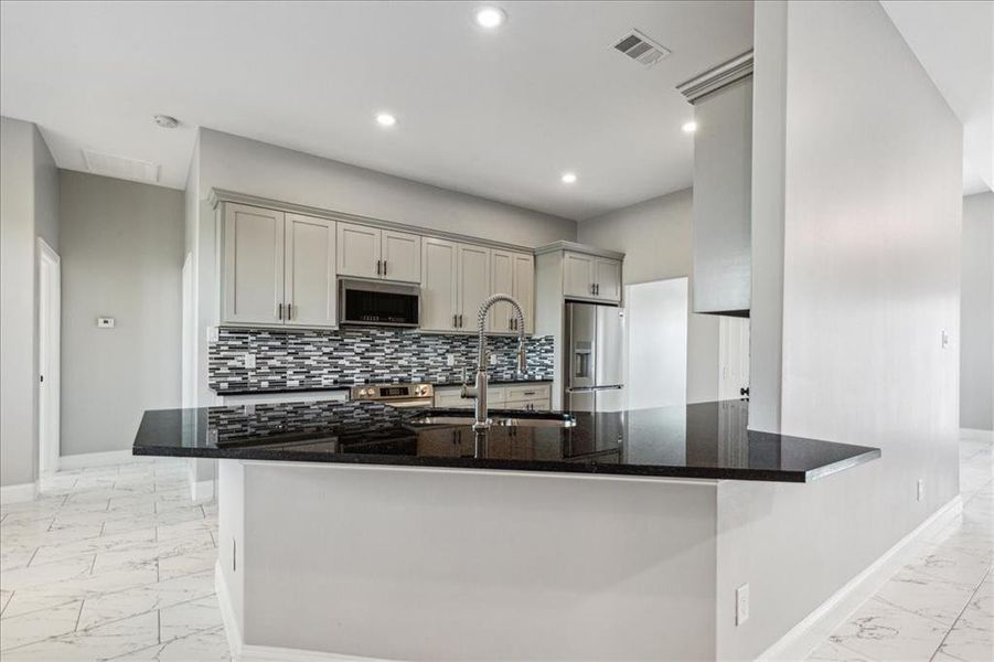 Kitchen with light tile flooring, kitchen peninsula, gray cabinetry, appliances with stainless steel finishes, and sink