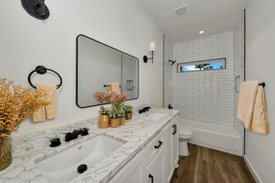 Full bathroom with toilet, double vanity, wood finished floors, and shower combination Full bathroom with toilet, double vanity, wood finished floors, and shower combination