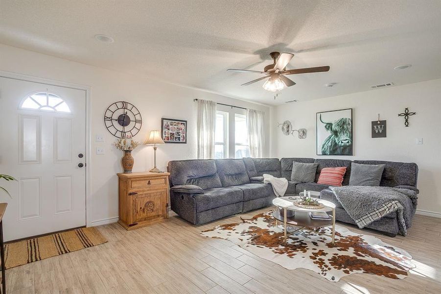 Living area featuring light wood-style tile floors, a ceiling fan and lots of natural light Living area featuring light wood-style tile floors, a ceiling fan and lots of natural light