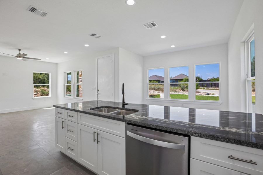 Gleaming dark stone countertops pair perfectly with modern cabinetry in this airy open-concept layout.