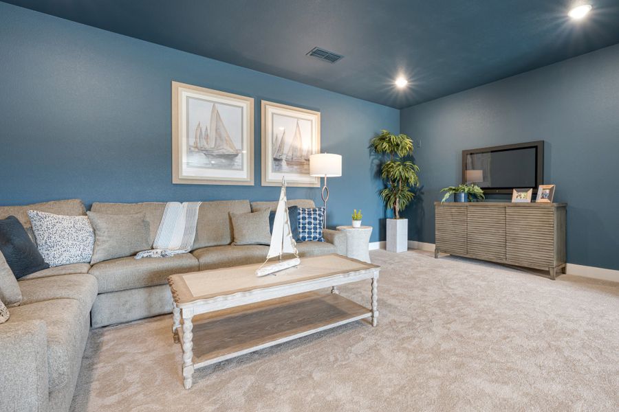 Living room with blue walls, sectional sofa, wood coffee table, and TV on dresser with nautical wall art