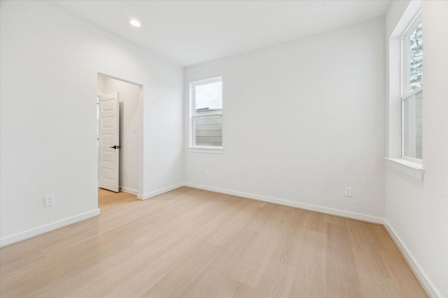 Secondary bedroom off the guest suite features a soothing neutral palette and warm natural light. Ideal for guests or a home office, it offers comfort and privacy with its attached ensuite bath.