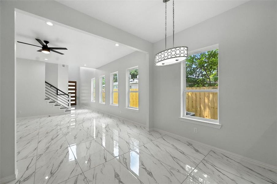 Unfurnished living room with plenty of natural light, light marble finish floors, stairs, and recessed lighting