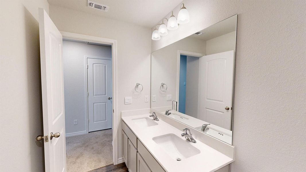 Bathroom featuring a double vanity with two sinks, a large mirror, and overhead lighting