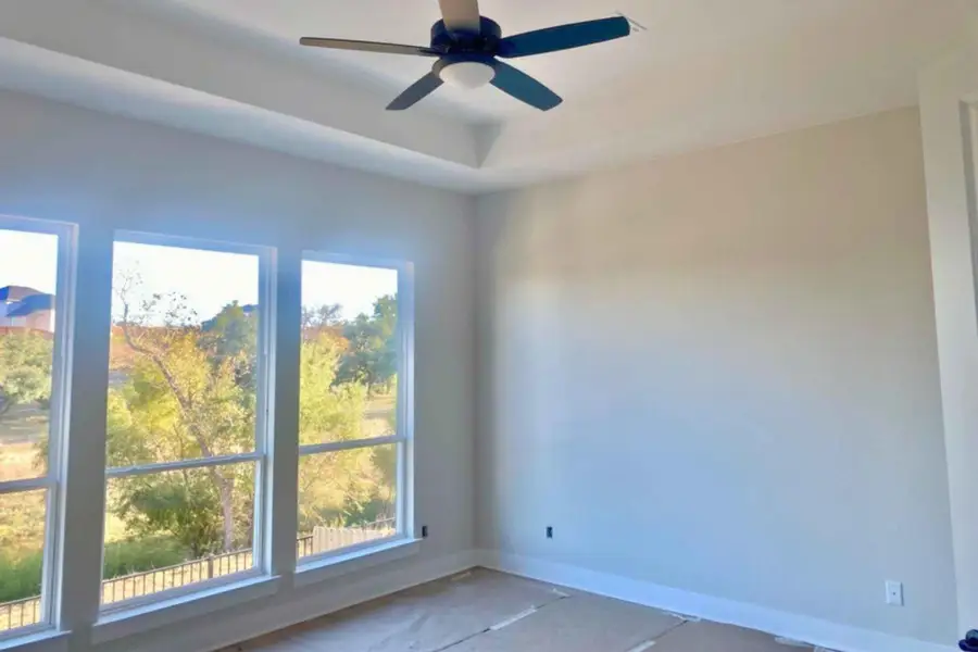 Empty room featuring ceiling fan and a tray ceiling