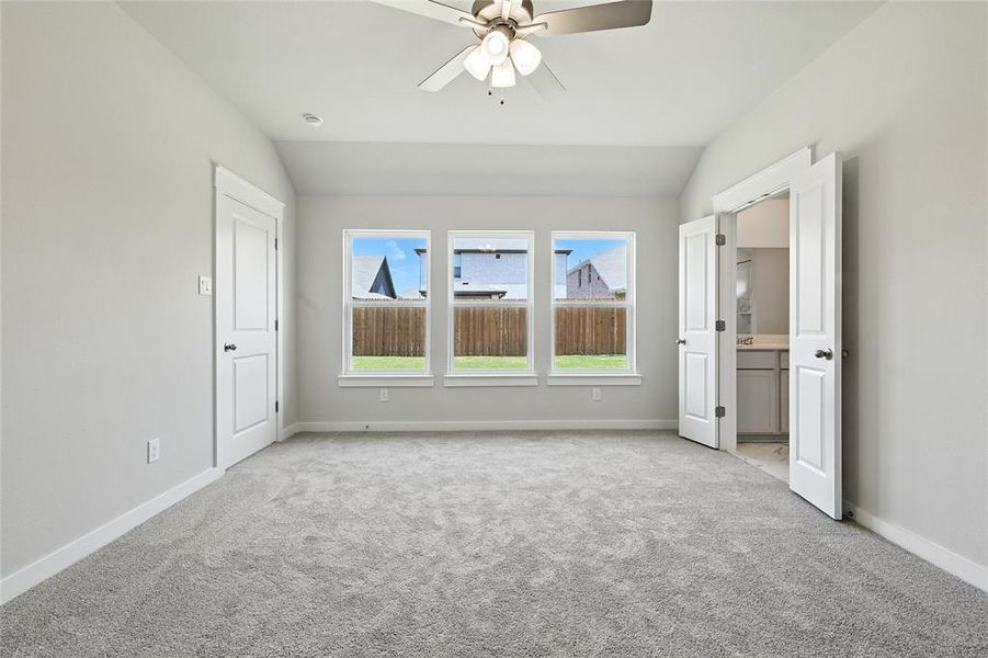 Unfurnished bedroom featuring light colored carpet, vaulted ceiling, and ceiling fan
