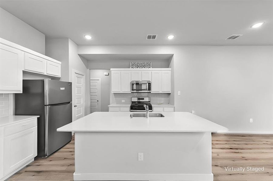 Kitchen with tasteful backsplash, an island with sink, stainless steel appliances, white cabinets, and recessed lighting Kitchen with tasteful backsplash, an island with sink, stainless steel appliances, white cabinets, and recessed lighting