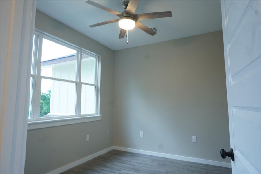 Unfurnished room with wood finished floors and a ceiling fan