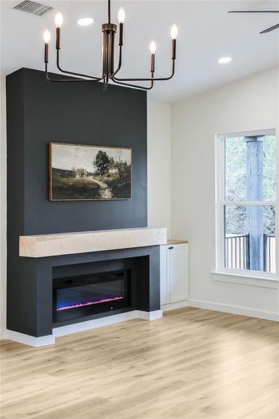 Detailed view of wood finished floors, a chandelier, a glass covered fireplace, and recessed lighting Detailed view of wood finished floors, a chandelier, a glass covered fireplace, and recessed lighting