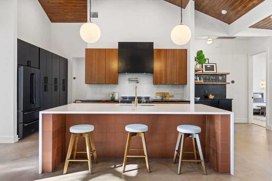 Kitchen with wooden ceiling, a kitchen breakfast bar, brown cabinetry, pendant lighting, and high vaulted ceiling