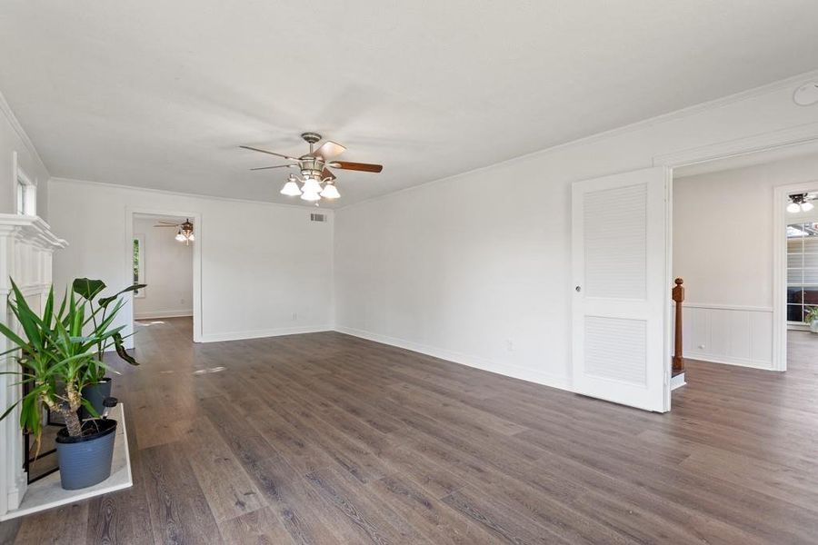 Unfurnished room with ceiling fan, dark wood-style floors, ornamental molding, and baseboards