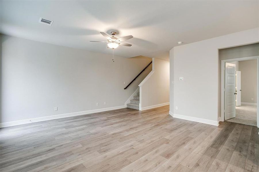 Empty room featuring ceiling fan, visible vents, baseboards, stairway, and light wood finished floors