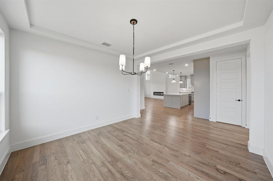 Unfurnished dining area featuring light wood-style flooring and a chandelier Unfurnished dining area featuring light wood-style flooring and a chandelier