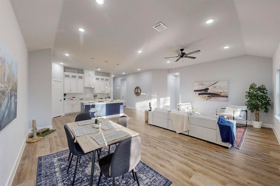 Dining room featuring vaulted ceiling, ceiling fan, sink, and light hardwood / wood-style floors