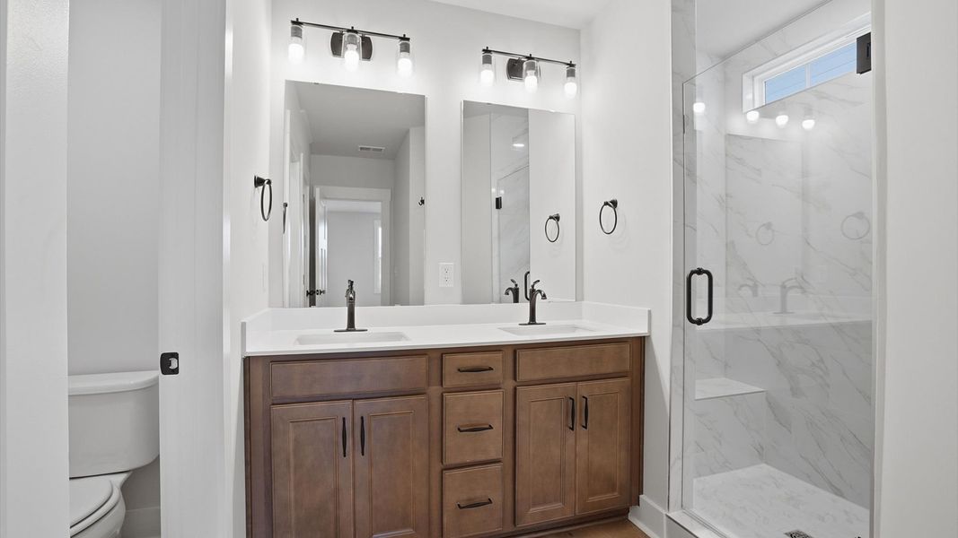 Highly functional and elegant en-suite with dual vanities, tiled walk-in shower, and refined finishes at Pelham Crossing