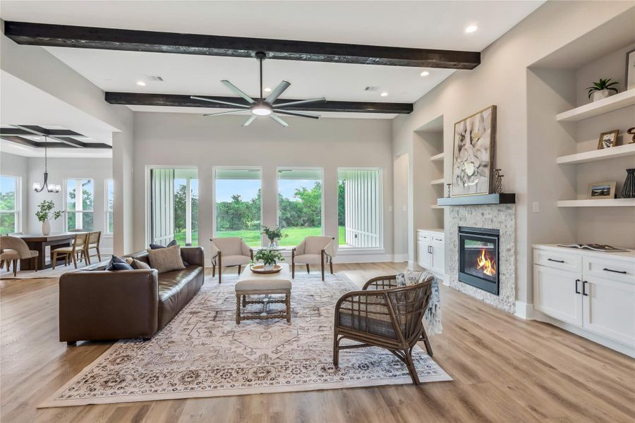 This spacious living area features an open floor plan with large windows offering scenic views, a cozy fireplace, and elegant wood flooring. This spacious living area features an open floor plan with large windows offering scenic views, a cozy fireplace, and elegant wood flooring.
