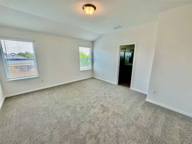 Unfurnished room with light carpet, vaulted ceiling, and a textured ceiling Unfurnished room with light carpet, vaulted ceiling, and a textured ceiling