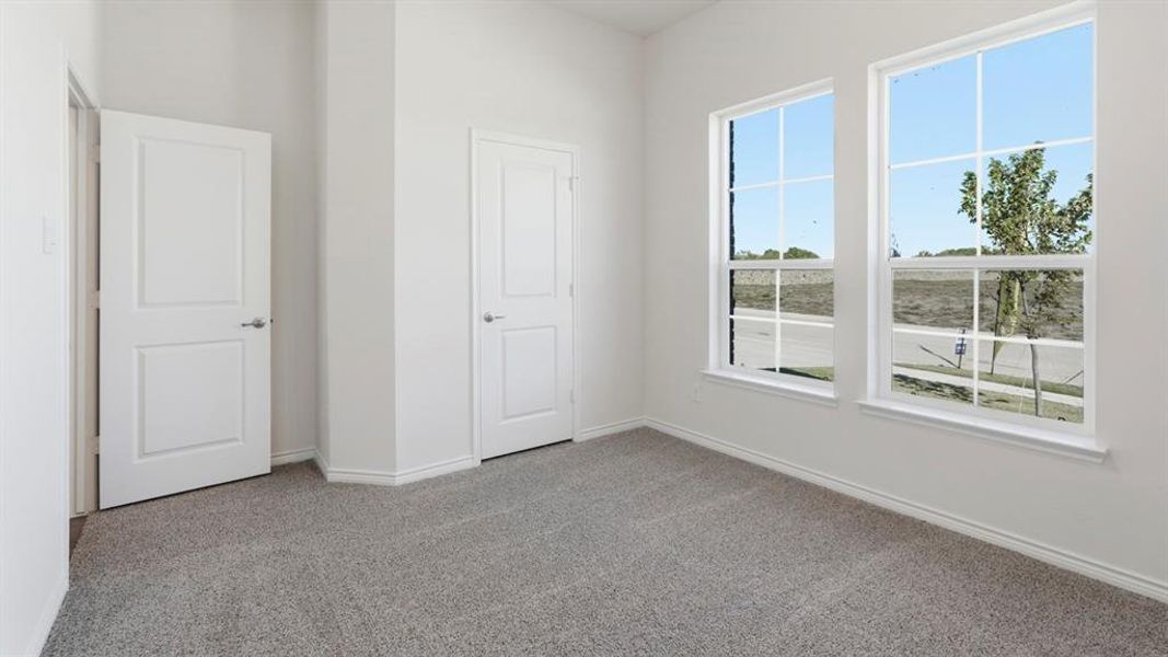 This room features light grey carpeting, white walls, and two white paneled doors This room features light grey carpeting, white walls, and two white paneled doors