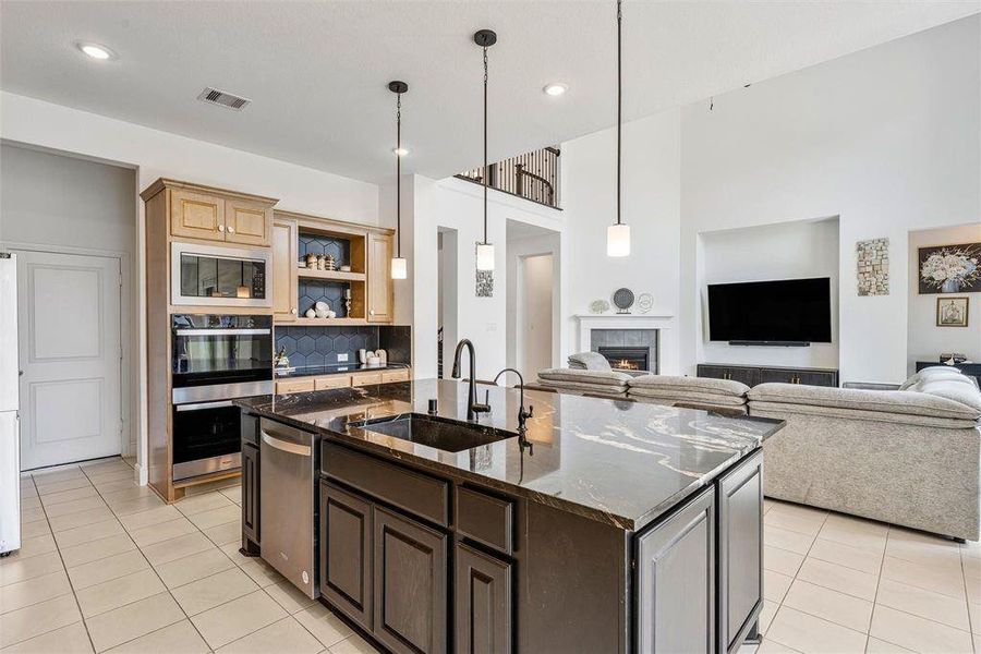 Gorgeous kitchen comes equipped with stainless steel appliances, beautiful natural wood cabinetry, granite countertops, a large eat-in island, 100 percent sink with drinking water and soap fixtures, a great sized pantry tucked behind the stove, and a pot filler over the stove for convenience.