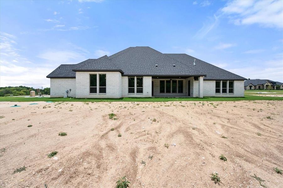 Rear exterior showcasing a white brick facade and a dark shingle roof
