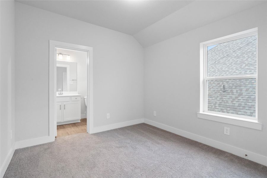 The ideal setup for multi-generational living or extended stays, this second-floor bedroom includes its own dedicated en suite bath, ensuring privacy for all. It features high ceilings, large window, plush carpet flooring, and neutral-toned walls.