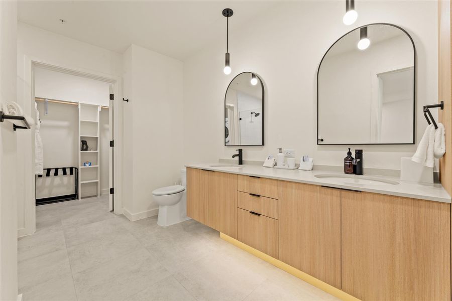 A contemporary double vanity pairs with clean architectural lines and an adjoining walk-in closet.