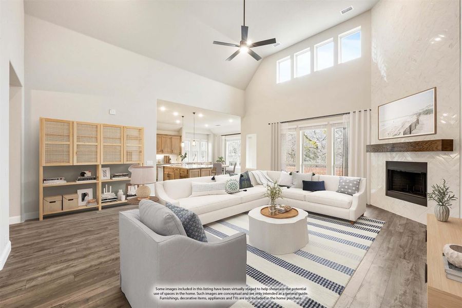 Living room with vaulted ceiling, ceiling fan, fireplace, and open view to kitchen with hardwood floors Living room with vaulted ceiling, ceiling fan, fireplace, and open view to kitchen with hardwood floors