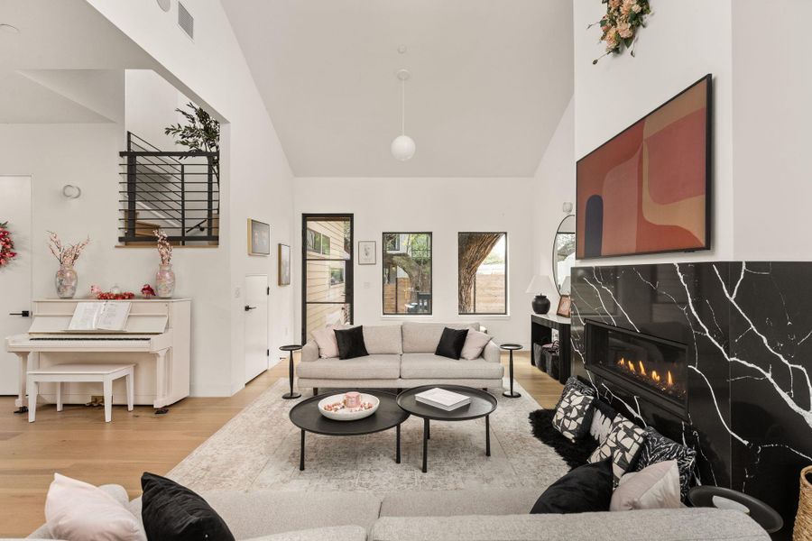 A well-lit gathering space with natural hardwood floors and a striking black marble fireplace. A well-lit gathering space with natural hardwood floors and a striking black marble fireplace.