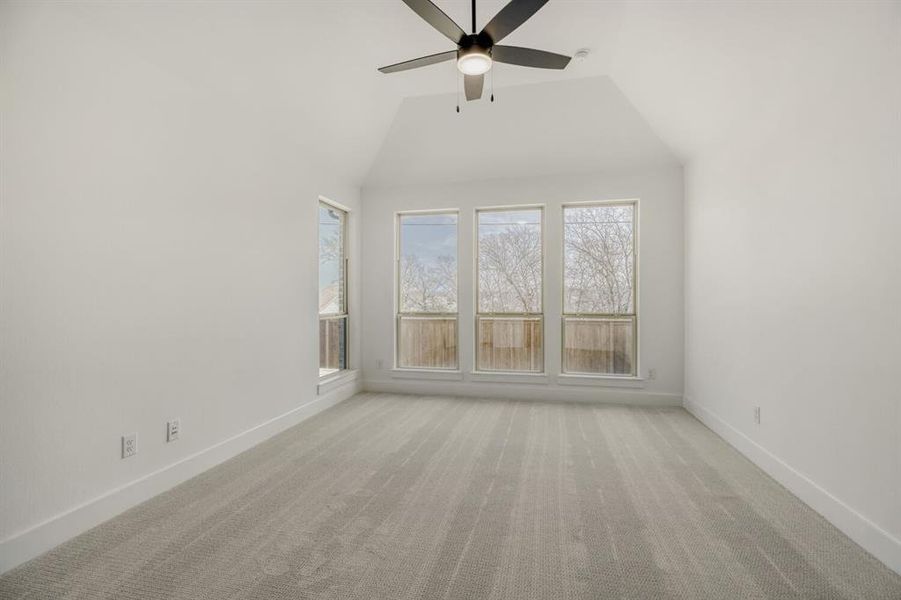 Empty room featuring light carpet, a ceiling fan, and lofted ceiling