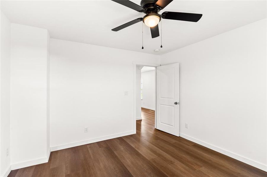 Interior room featuring wood-finish flooring, white walls, and a contemporary ceiling fan with integrated lighting