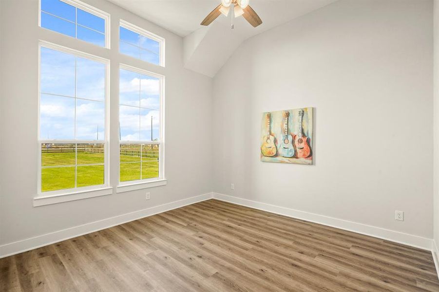 This Secondary Bedroom comes equipped with LVP flooring, high ceilings, a ceiling fan, and spacious walk-in closet. The two windows, with transoms above, provide a breathtaking view of the sprawling Front Yard. This Bedroom has access to the Secondary Bathroom next-door.