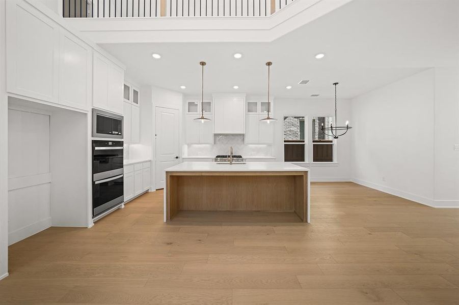 Kitchen featuring white cabinets, an island with sink, decorative light fixtures, recessed lighting, and backsplash