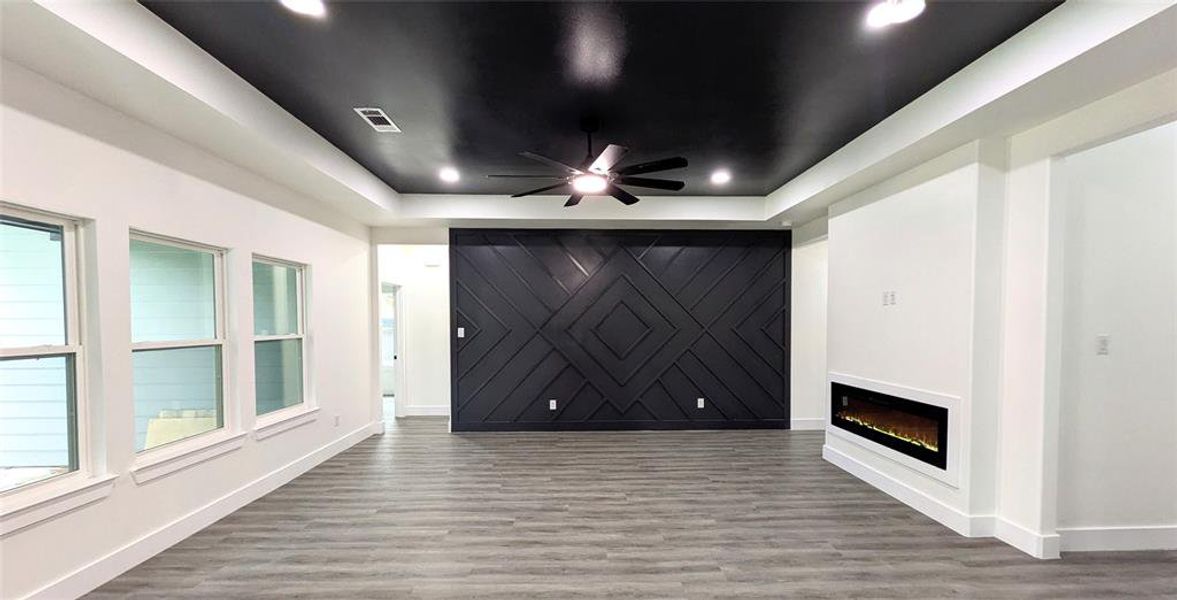 Unfurnished living room with baseboards, ceiling fan, visible vents, and wood finished floors