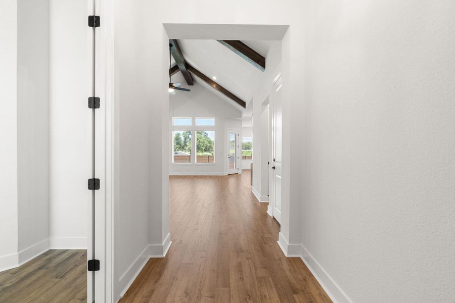 A welcoming entryway with rich wood flooring leads to a  living area featuring vaulted ceilings.