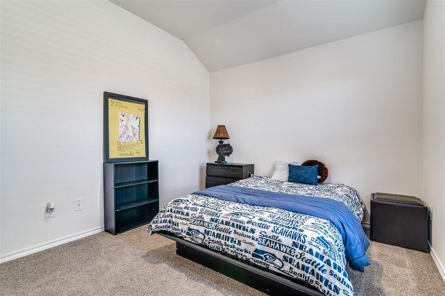 Carpeted bedroom featuring lofted ceiling and baseboards