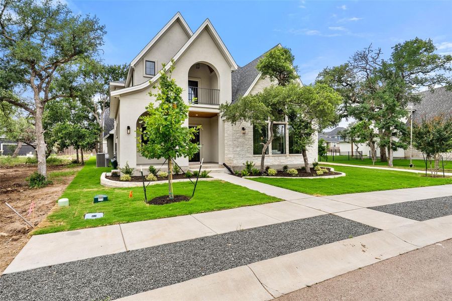 A graceful home featuring gabled roofs and a charming balcony overlooking manicured lawns.